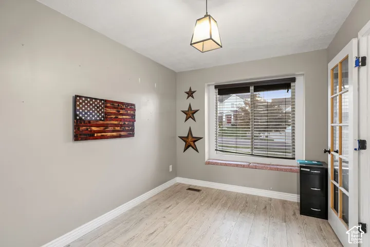 Wood-finish flooring, built-in window bench with brick-style detailing, geometric pendant lighting, and a multi-pane glass-panel door