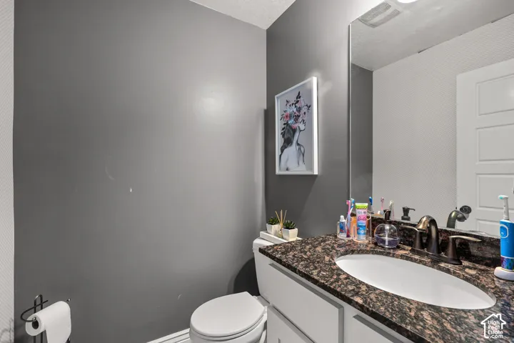 Bathroom featuring a stone-surface vanity with an integrated oval sink, oil-rubbed bronze faucet, and a wall-to-wall mirror