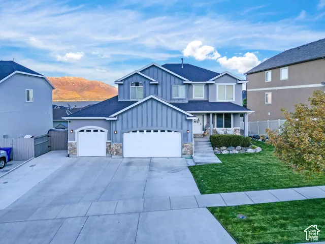 Two-story residence featuring vertical siding, stone masonry accents, a three-car garage, and a concrete driveway
