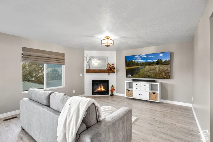 Corner fireplace with white brick surround, wood-finish mantel, and wood-finish flooring throughout