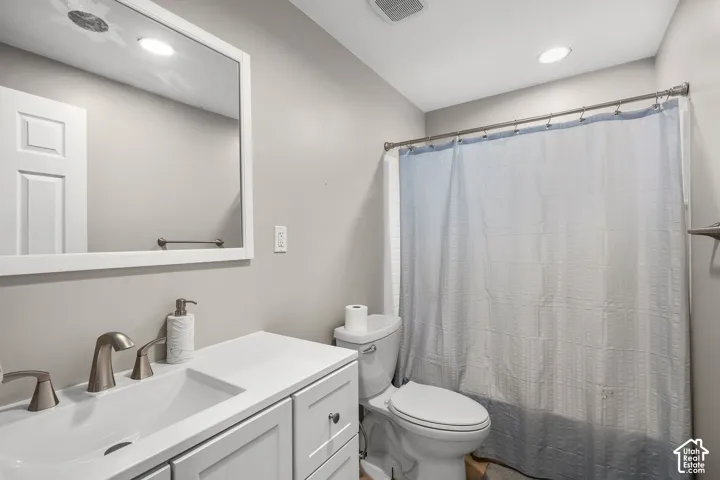 Bathroom featuring a white vanity with an integrated basin, countertop, brushed-nickel widespread faucet, framed wall mirror, and tub-shower combination with a curtain rod