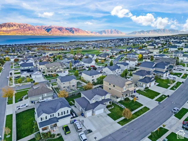 Aerial perspective featuring residential lots with multi-level homes, paved streets, and a mountainous backdrop