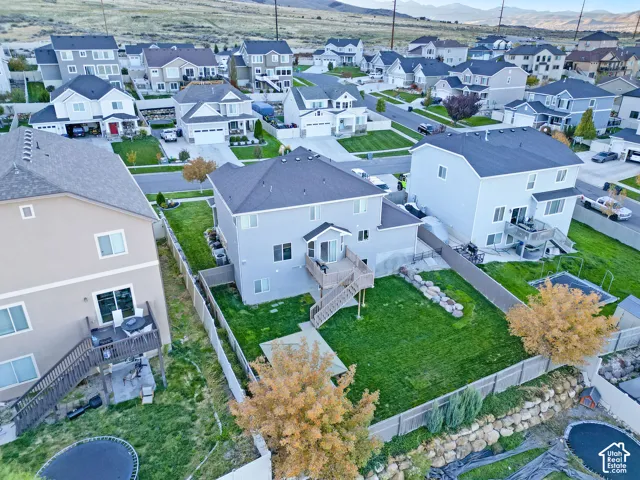 Two-story residence featuring an elevated wood deck, stairs providing ground-level access, fenced backyard, manicured lawn, and mountain backdrop