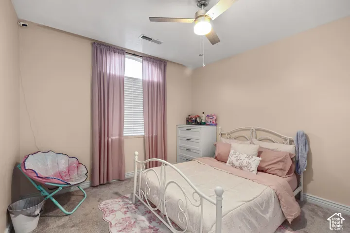 Neutral-toned room featuring wall-to-wall carpeting, an arched window, and a ceiling-mounted light fixture with a fan
