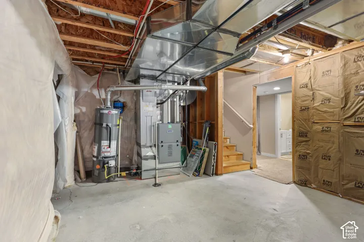 Mechanical utility area featuring a central furnace, water heater, exposed ductwork, and fiberglass batt wall insulation