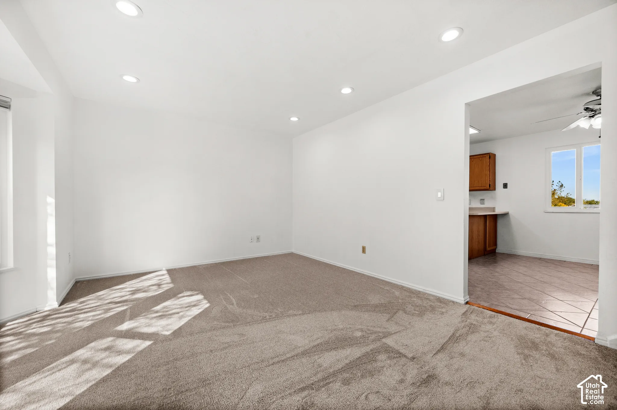 Neutral carpeted flooring, recessed lighting, and a windowed kitchen area featuring tile flooring and wooden cabinetry