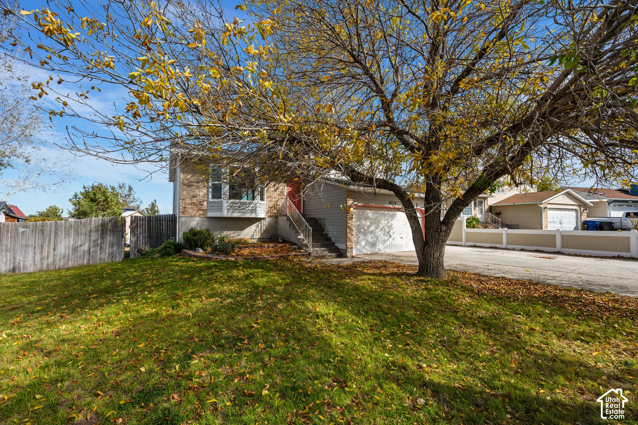 Exterior featuring brick and horizontal siding, a two-car attached garage, bay window, concrete driveway, and mature landscaping