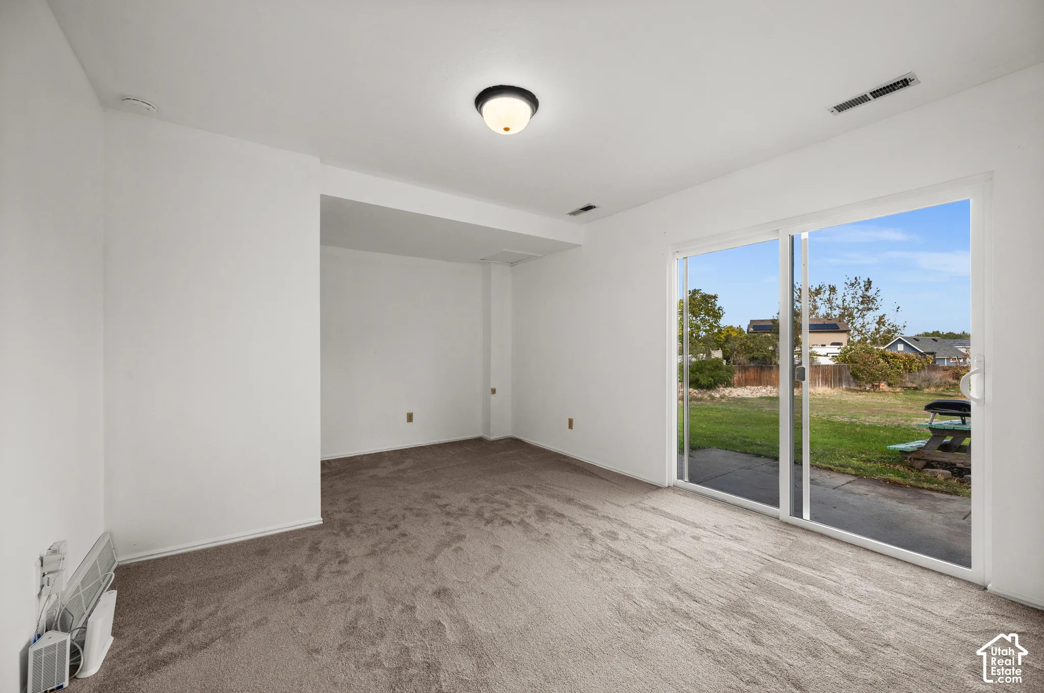 Room featuring neutral carpeting, a flush-mount ceiling light fixture, and a large sliding glass door providing access to the exterior