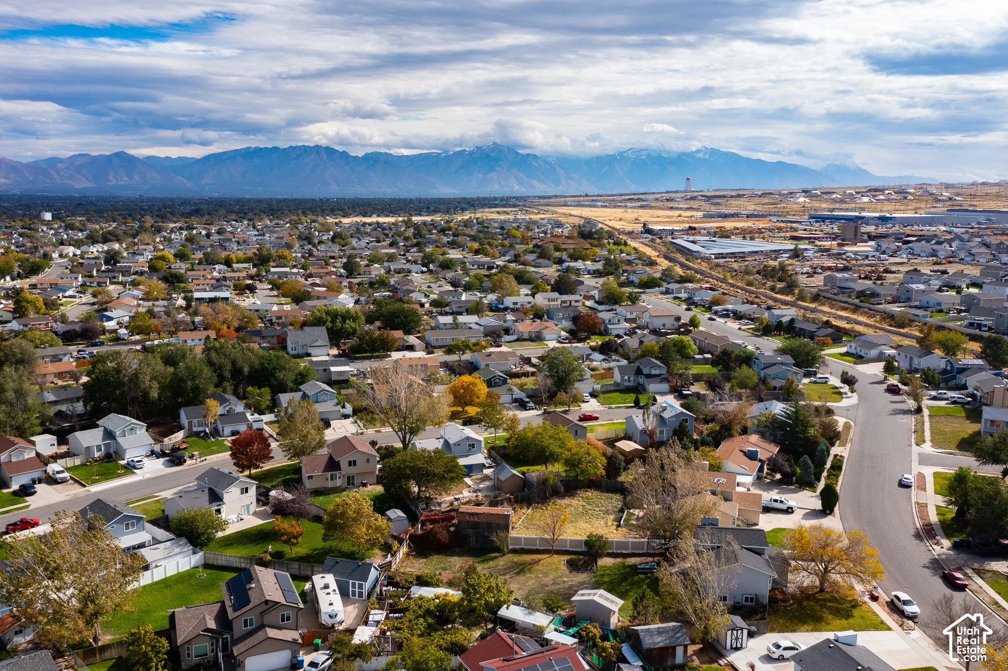 Aerial perspective of the residential area featuring a mountain range backdrop and mature trees