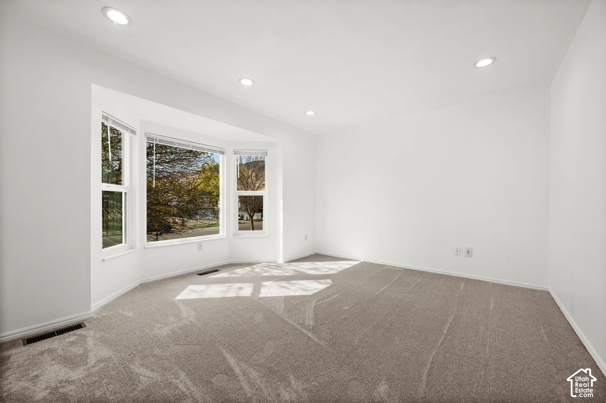 Interior space featuring a bay window, recessed ceiling lighting, and neutral carpeting