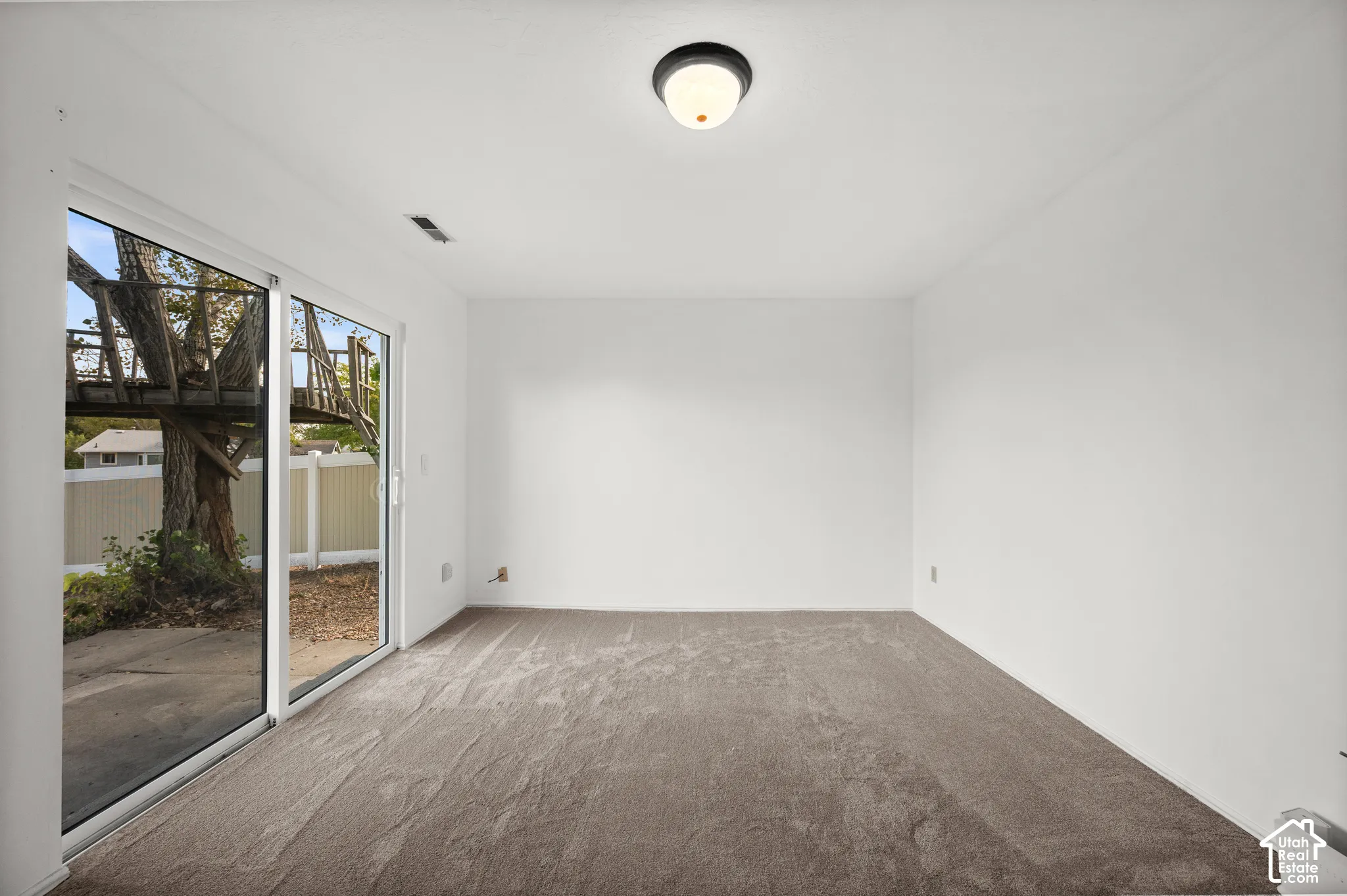 Neutral-toned carpeting, sliding glass doors, and flush-mount ceiling lighting