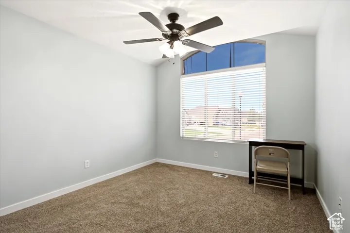Room featuring neutral wall tones, plush carpeting, a vaulted ceiling, a ceiling fan with integrated lighting, and an arched window with horizontal blinds
