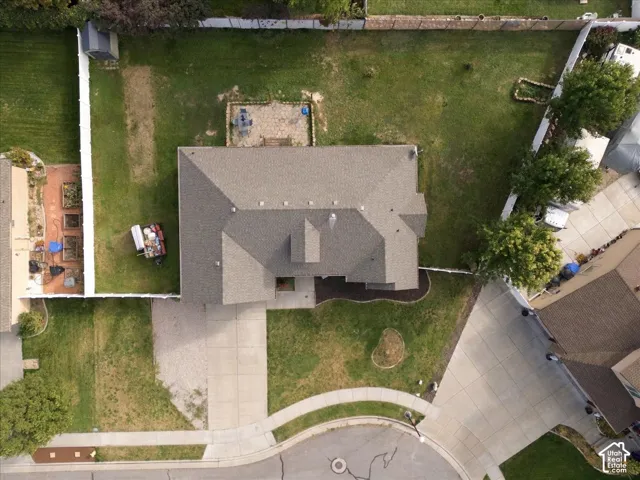 Aerial view of property featuring a fenced backyard, stone-paver patio, concrete driveway, and mature trees