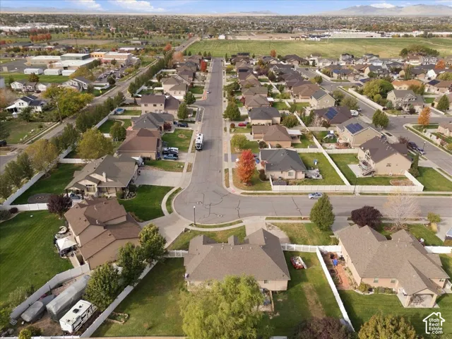 Aerial view of residential neighborhood featuring paved streets, suburban housing lots, white perimeter fencing, and mature trees