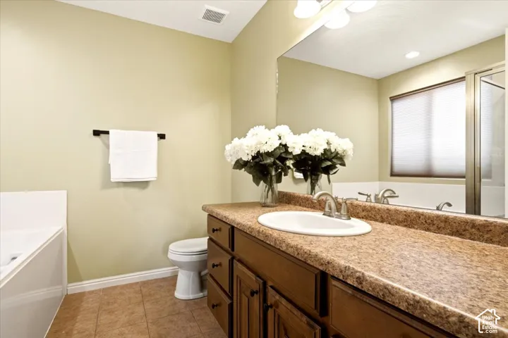 Bathroom vanity featuring wood-finish cabinetry, a textured countertop with an integrated basin, a full-width wall mirror, and tile flooring