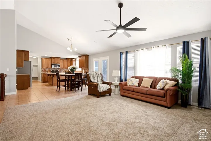 Vaulted ceilings featuring a modern multi-blade ceiling fan, expansive windows with integrated blinds, and cabinetry with an island workspace
