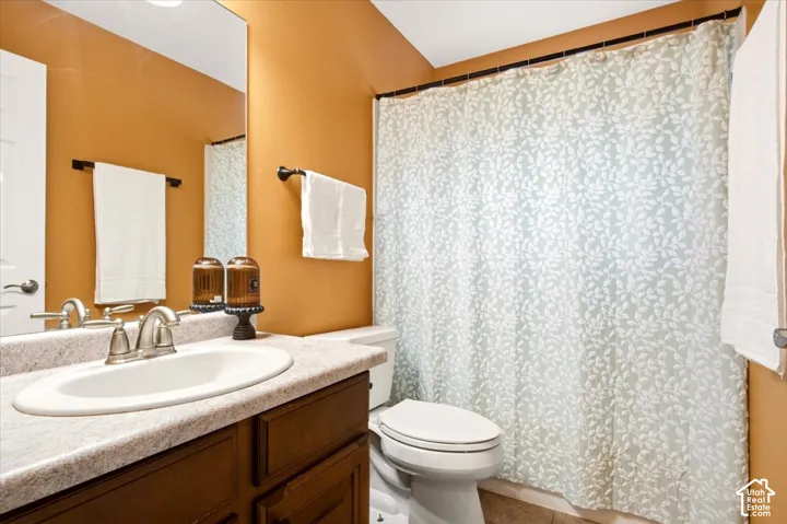 Bathroom featuring a wood vanity with a stone-finish countertop, integrated oval basin, polished metal faucet, and a large wall-mounted mirror