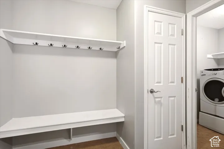 Built-in white storage bench with integrated shelving and seven decorative metal wall hooks