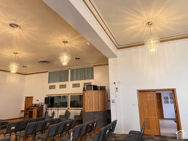 High ceilings with detailed crown molding, multi-tiered crystal pendant lighting, wooden-panel doors, and integrated wall windows