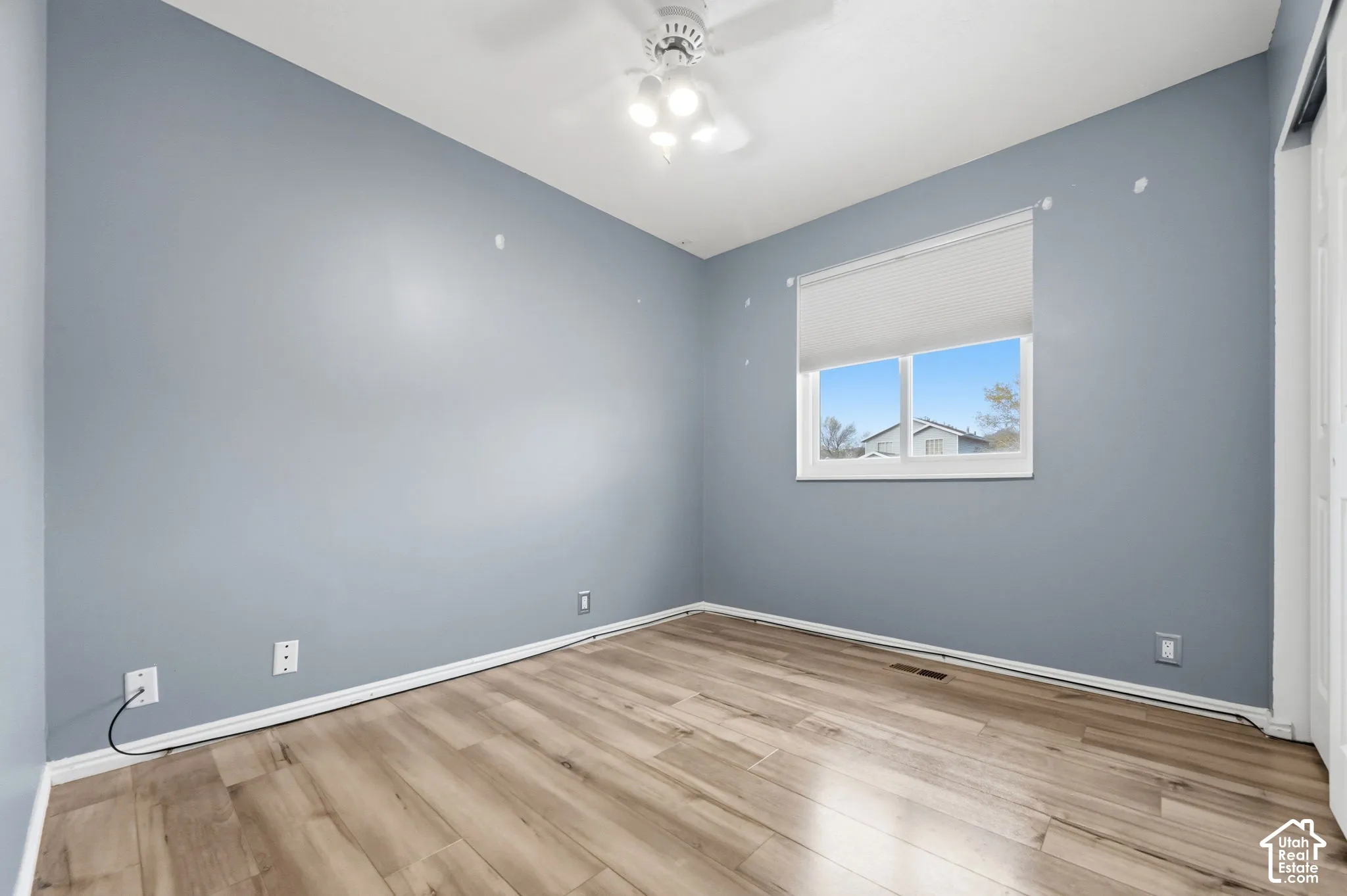 Bedroom featuring wood-finish flooring, neutral-toned walls, a single-pane sliding window with a built-in blind, and a central ceiling fan with multi-directional lighting