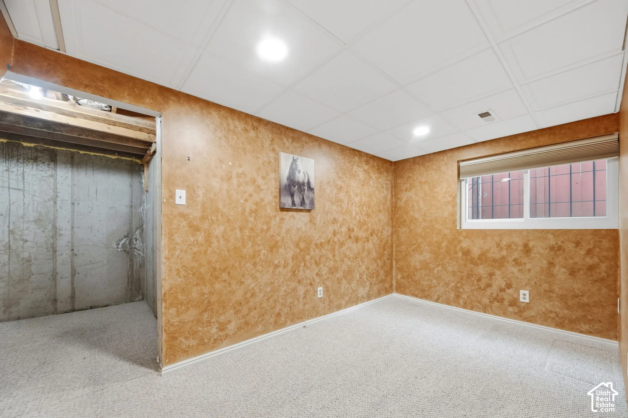 Interior space featuring textured wall finishes, neutral carpeting, recessed lighting, and a window with a fitted roller shade