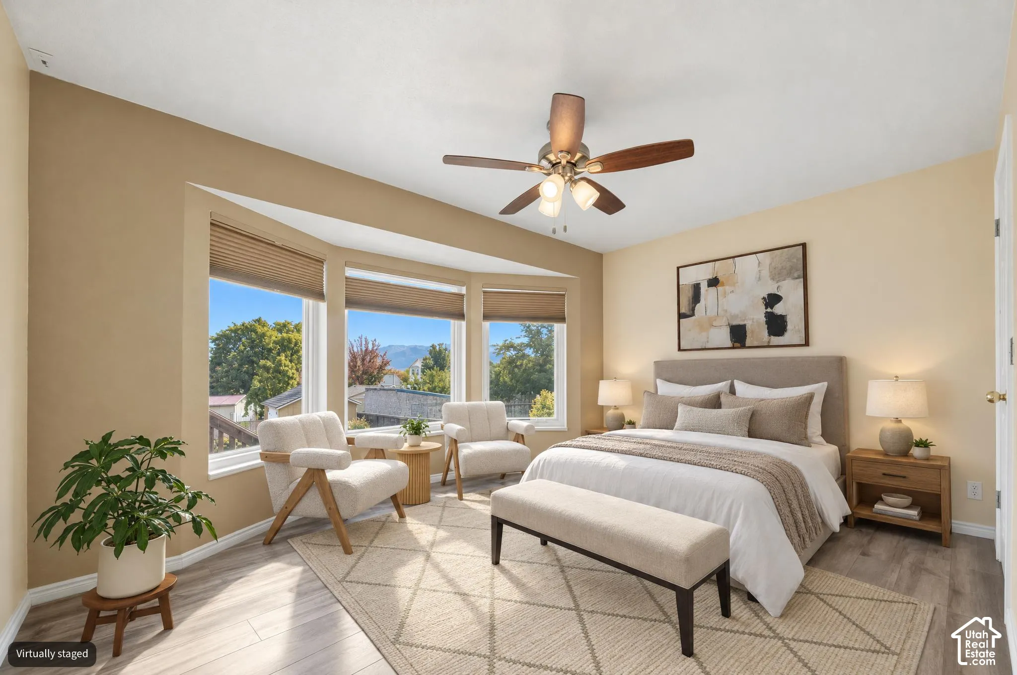 Digitally altered bedroom with bay window featuring three individual glass panels, light-toned wood-finish flooring, and a central ceiling fan with integrated lighting