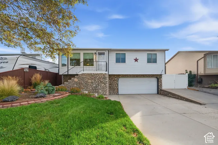 Rambler exterior featuring horizontal siding, a river rock stone foundation, a two-car garage, and a concrete driveway