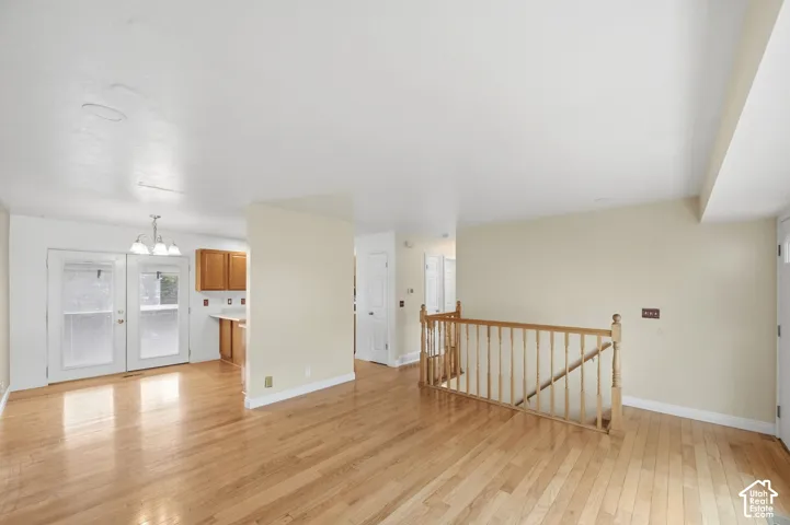 Open-concept interior featuring wood-finish flooring, a wood-railing staircase, double glass-panel doors, and natural wood cabinetry