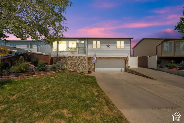 Rambler, exterior featuring horizontal siding, a river rock stone facade, a multi-car garage, and concrete driveway
