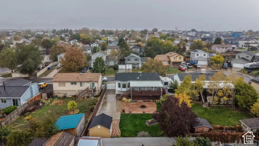 Aerial perspective of a property featuring an elevated rear deck, stamped concrete patio, lawn area, and a detached storage structure
