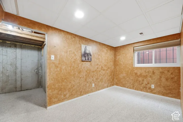 Interior space featuring textured wall finishes, neutral carpeting, recessed lighting, and a window with a fitted roller shade