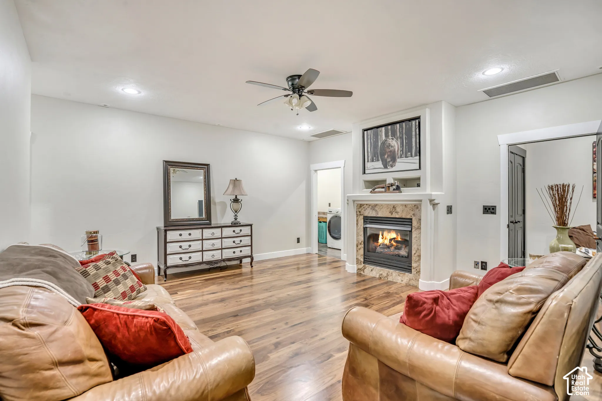 Living area featuring wood-finish flooring, a stone-surround fireplace with built-in mantel and recessed display shelving, recessed lighting, and a ceiling fan