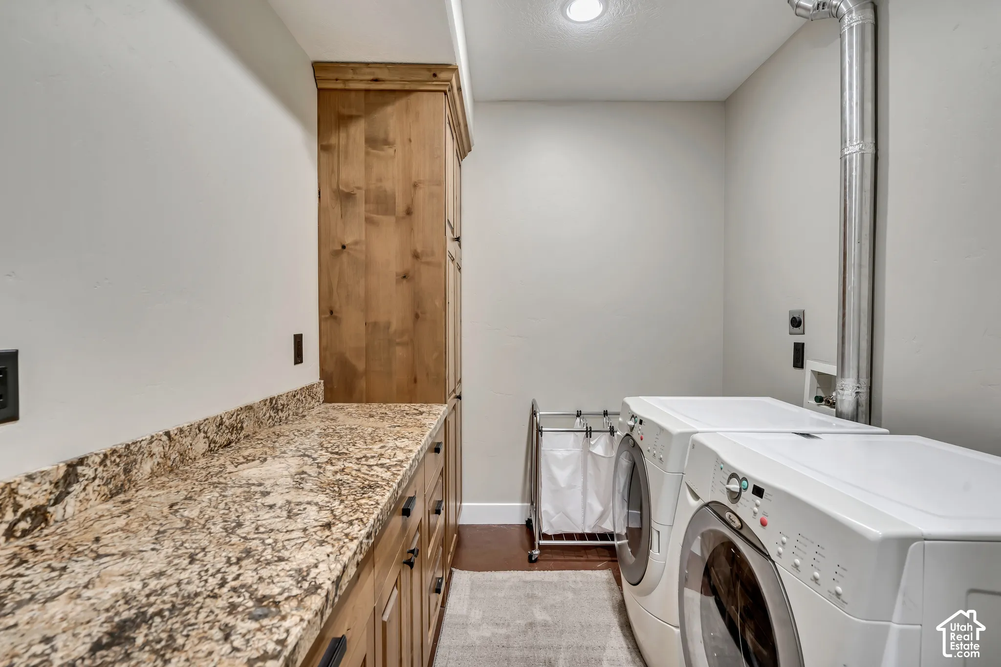 Laundry area featuring custom wood cabinetry, stone-finish countertops, and wood-finish flooring
