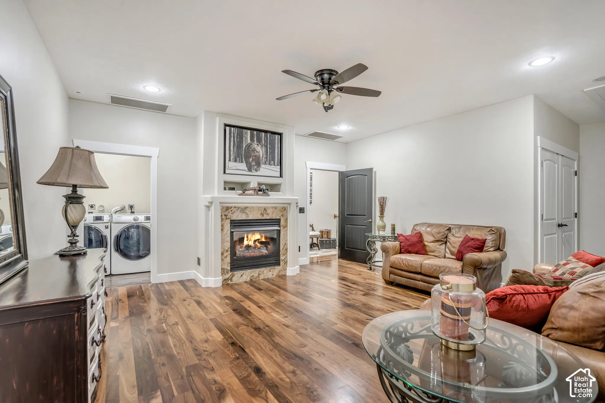 Fireplace featuring stone-tile surround and built-in shelving, wood-finish flooring, ceiling fan with light fixture, and recessed lighting
