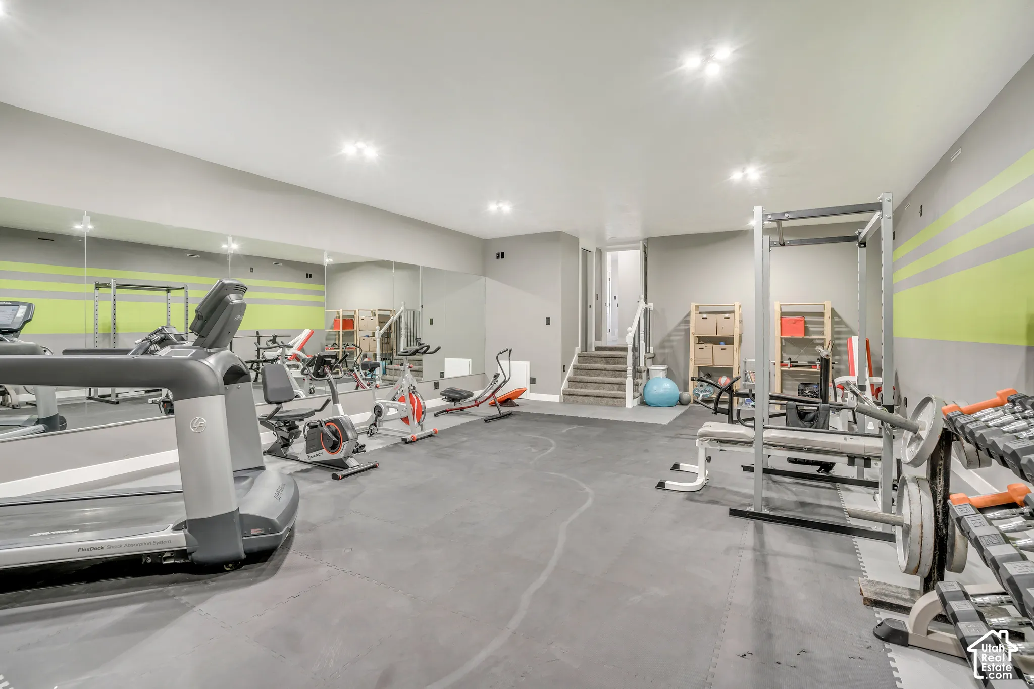 Finished room featuring large wall-mounted mirrors, recessed lighting, and rubber flooring
