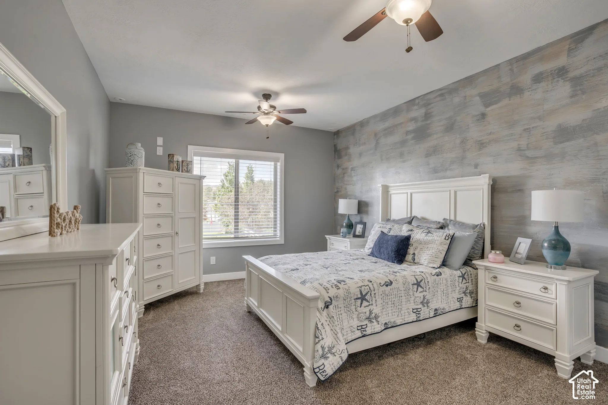 Bedroom featuring a textured wood-finish accent wall, dual ceiling fans with integrated lighting, and neutral carpeting
