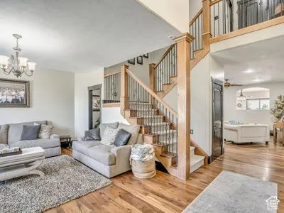 Open-concept floor plan with wood-finish flooring, soaring vaulted ceilings, and a central staircase featuring custom wood railings with iron balusters