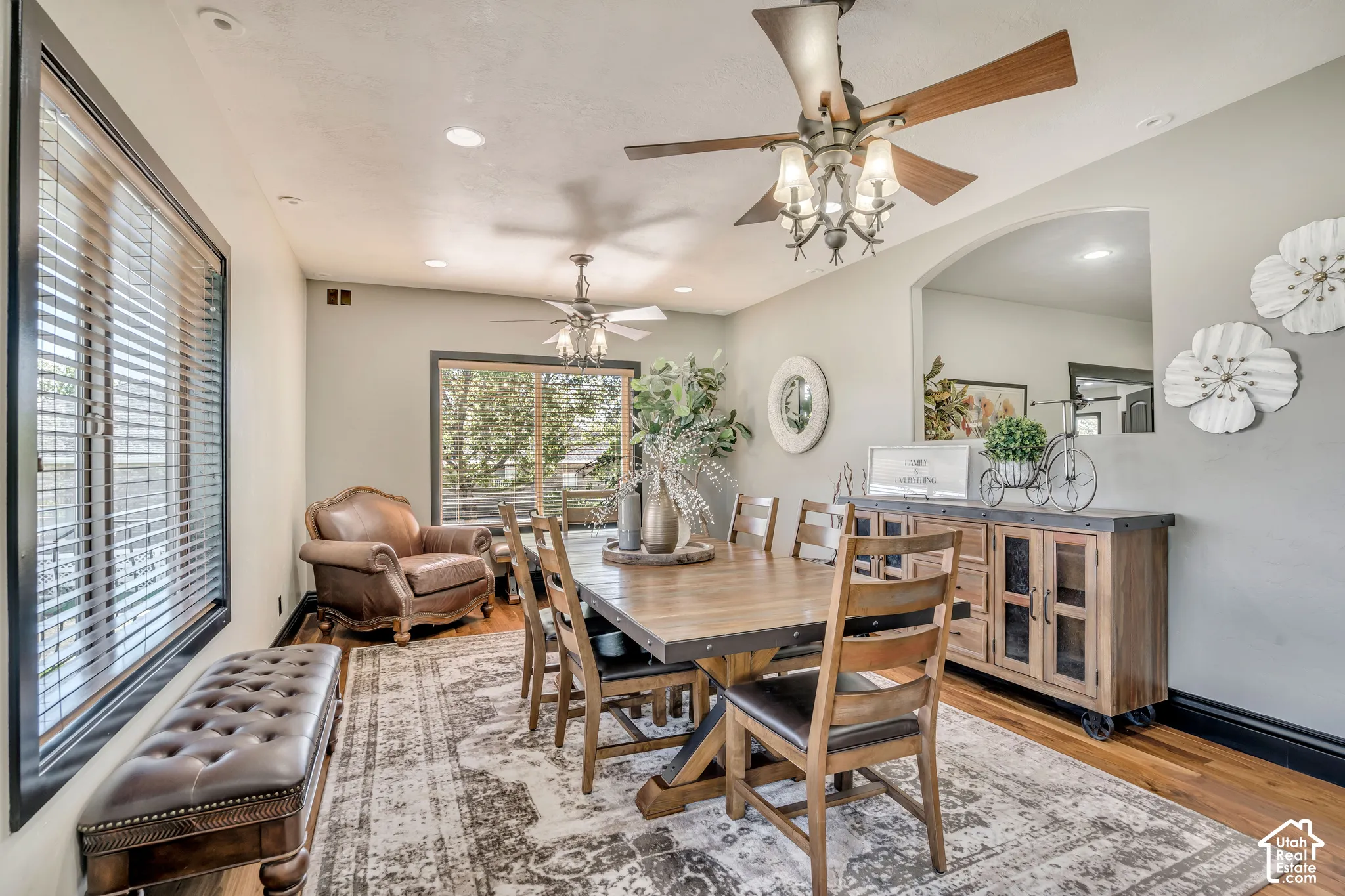 Dining area featuring dual ceiling fans with integrated lighting, recessed lighting, wood-finish flooring, and a large arched wall niche