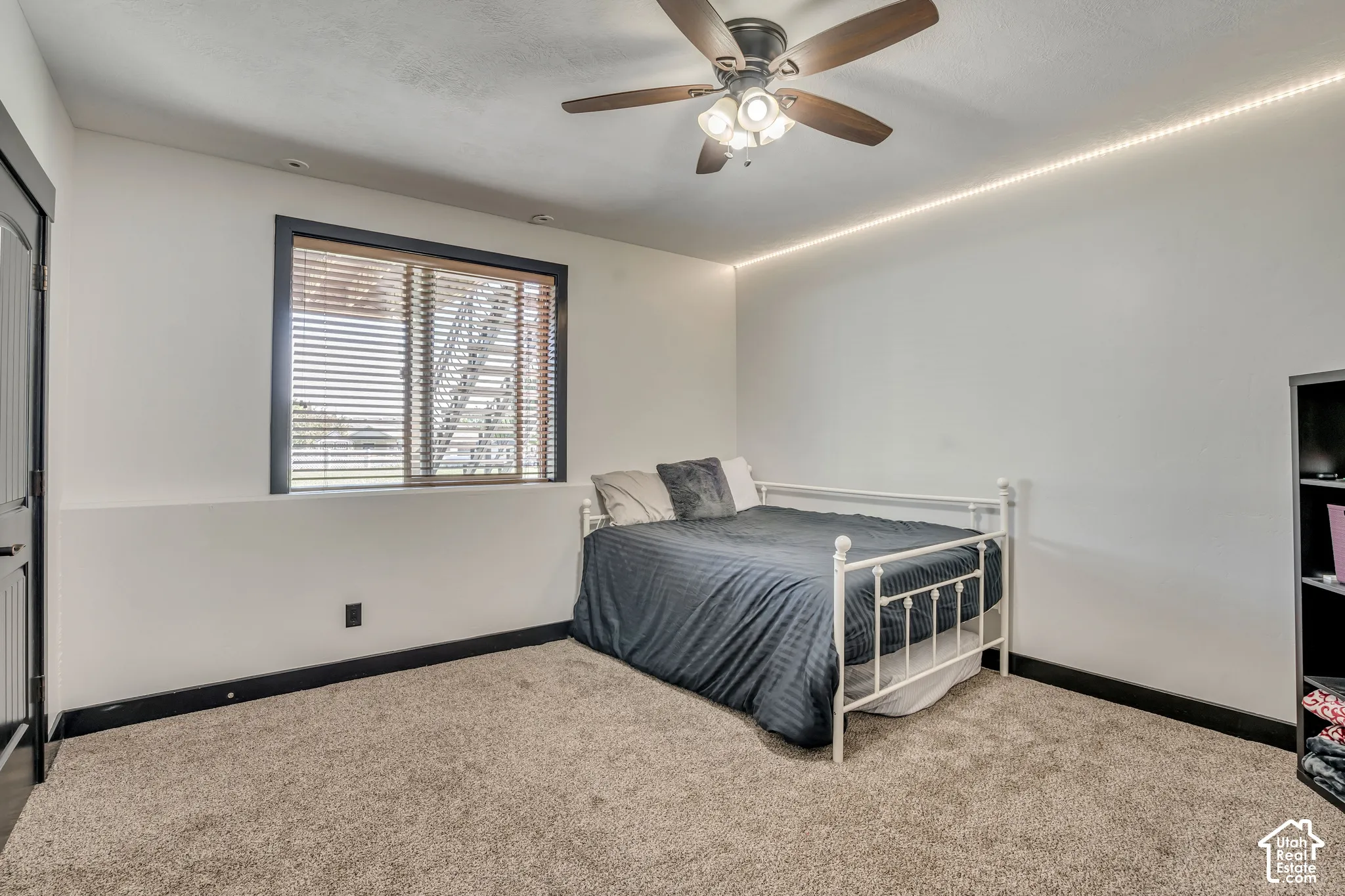 Neutral-toned carpeting, ceiling fan with integrated lighting, recessed wall-mounted LED accent lighting, and window with dark-finish trim