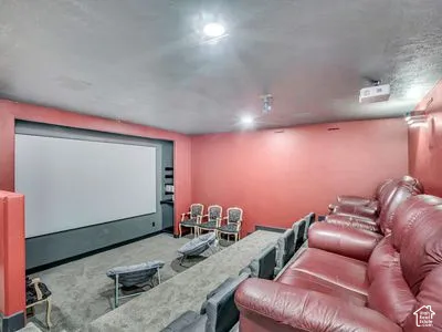Media room featuring a recessed projector screen, tiered floor levels, ceiling-mounted projection equipment, and recessed lighting