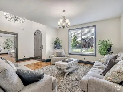Arched wood-finish entry door, custom dark-toned interior trim, polished wood-finish flooring, and multi-light chandelier fixtures