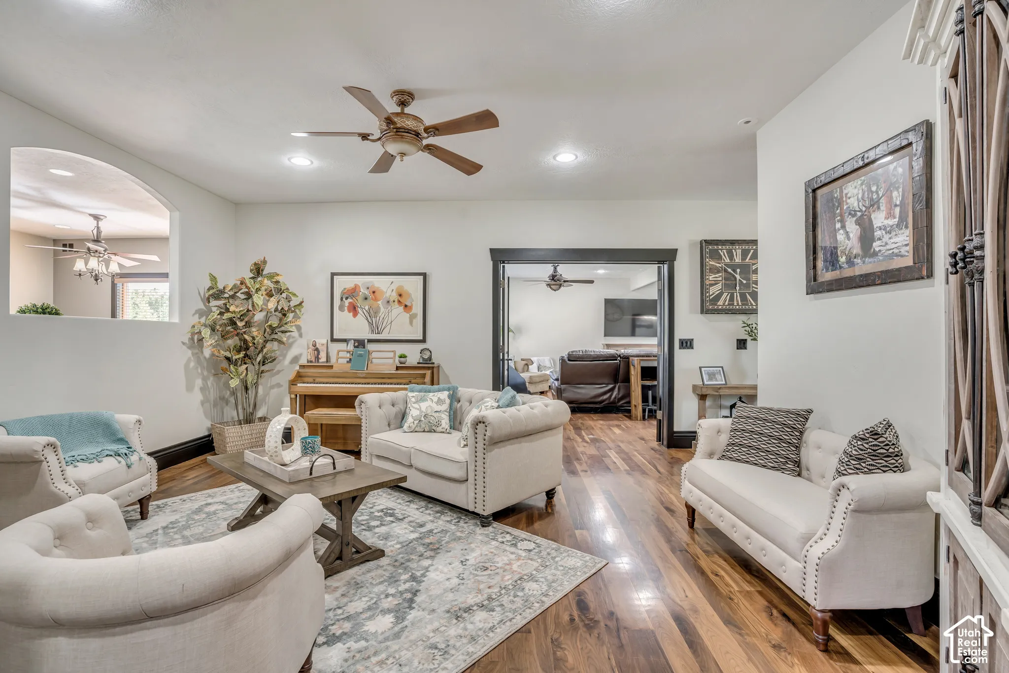 Living area featuring wood-finish flooring, recessed lighting, a ceiling fan, arched wall cutout, and dark-finished doorway trim