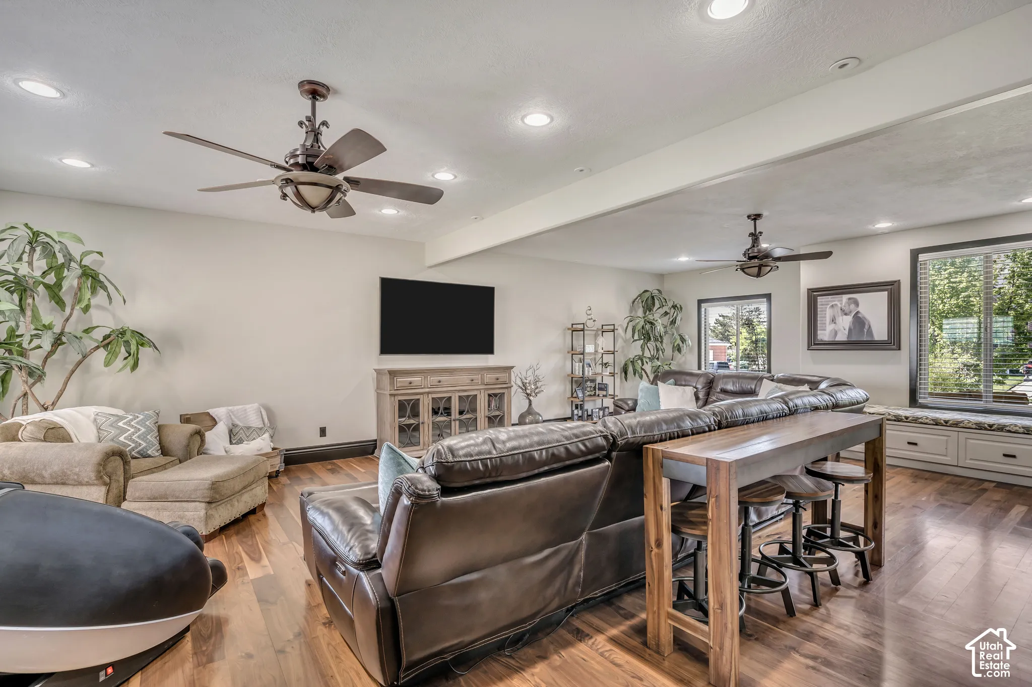 Wood-finish flooring, recessed lighting, dual ceiling fans, and built-in window seating with lower storage cabinetry