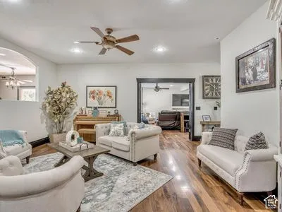 Living area featuring wood-finish flooring, a ceiling fan, recessed lighting, and a prominent arched entryway
