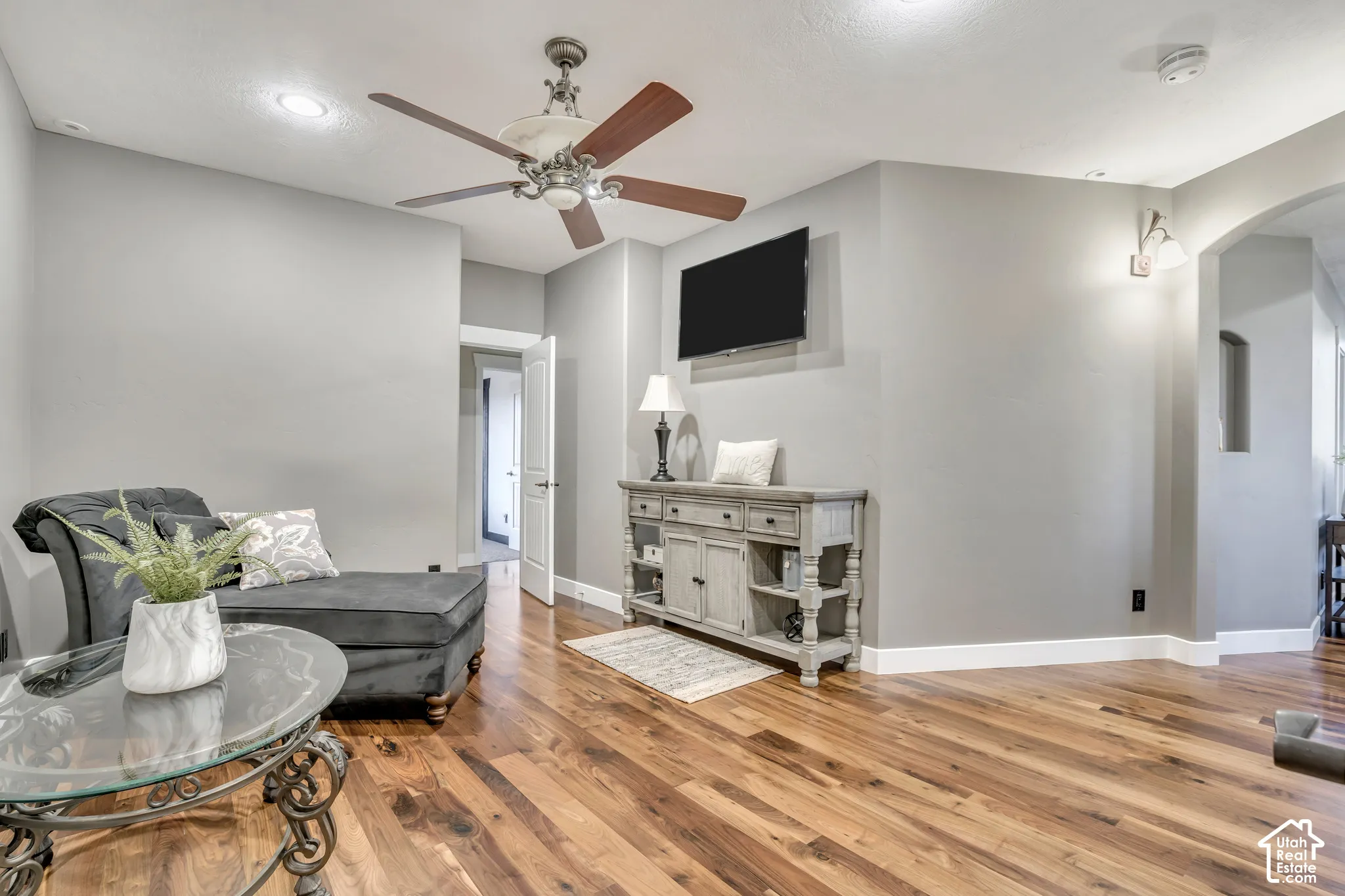 Wood-finish flooring, recessed lighting, arched entryway, and ceiling fan with integrated light fixture