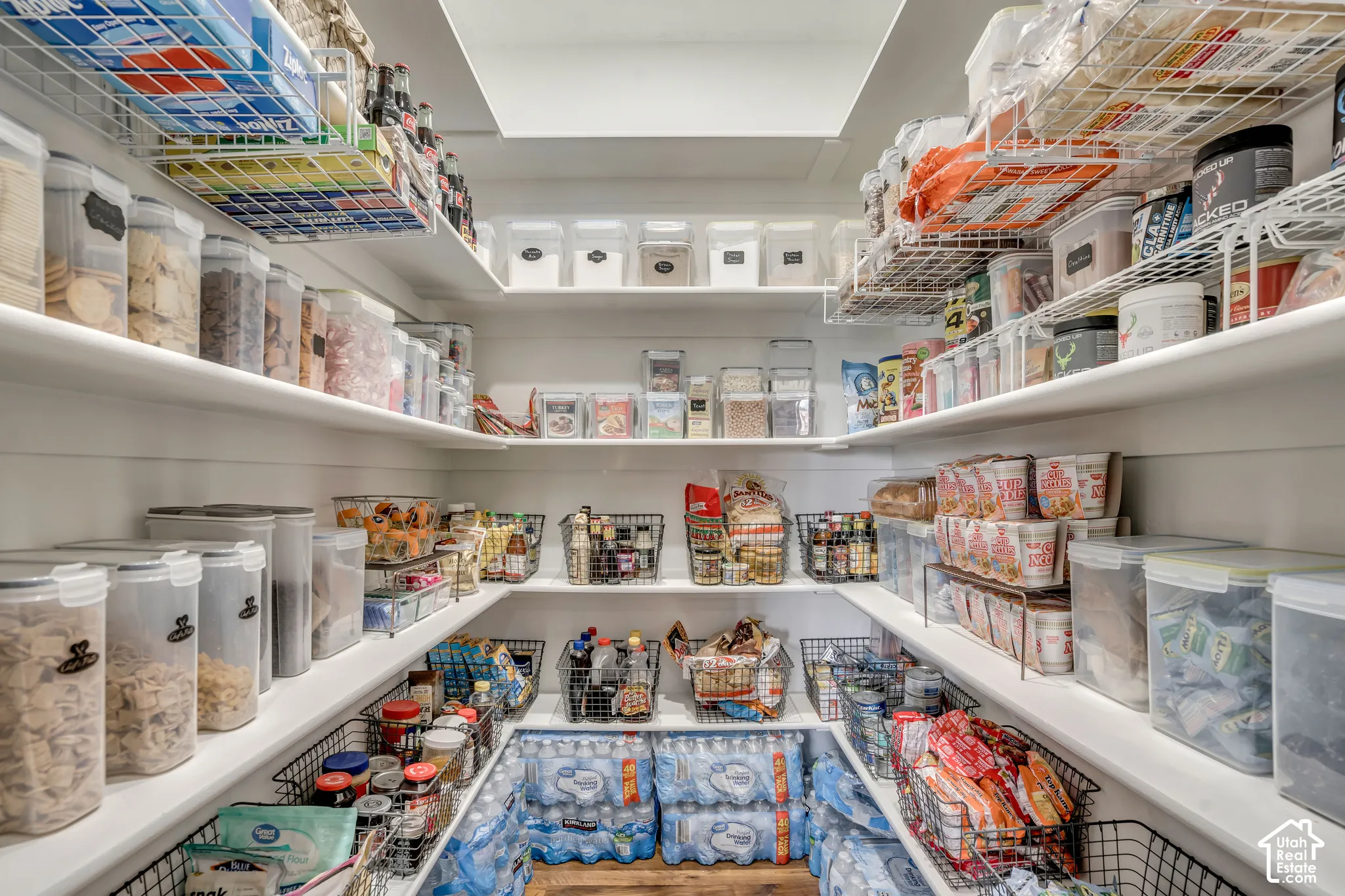 Walk-in pantry featuring white shiplap walls, multi-level fixed shelving, wire storage racks, and overhead recessed lighting