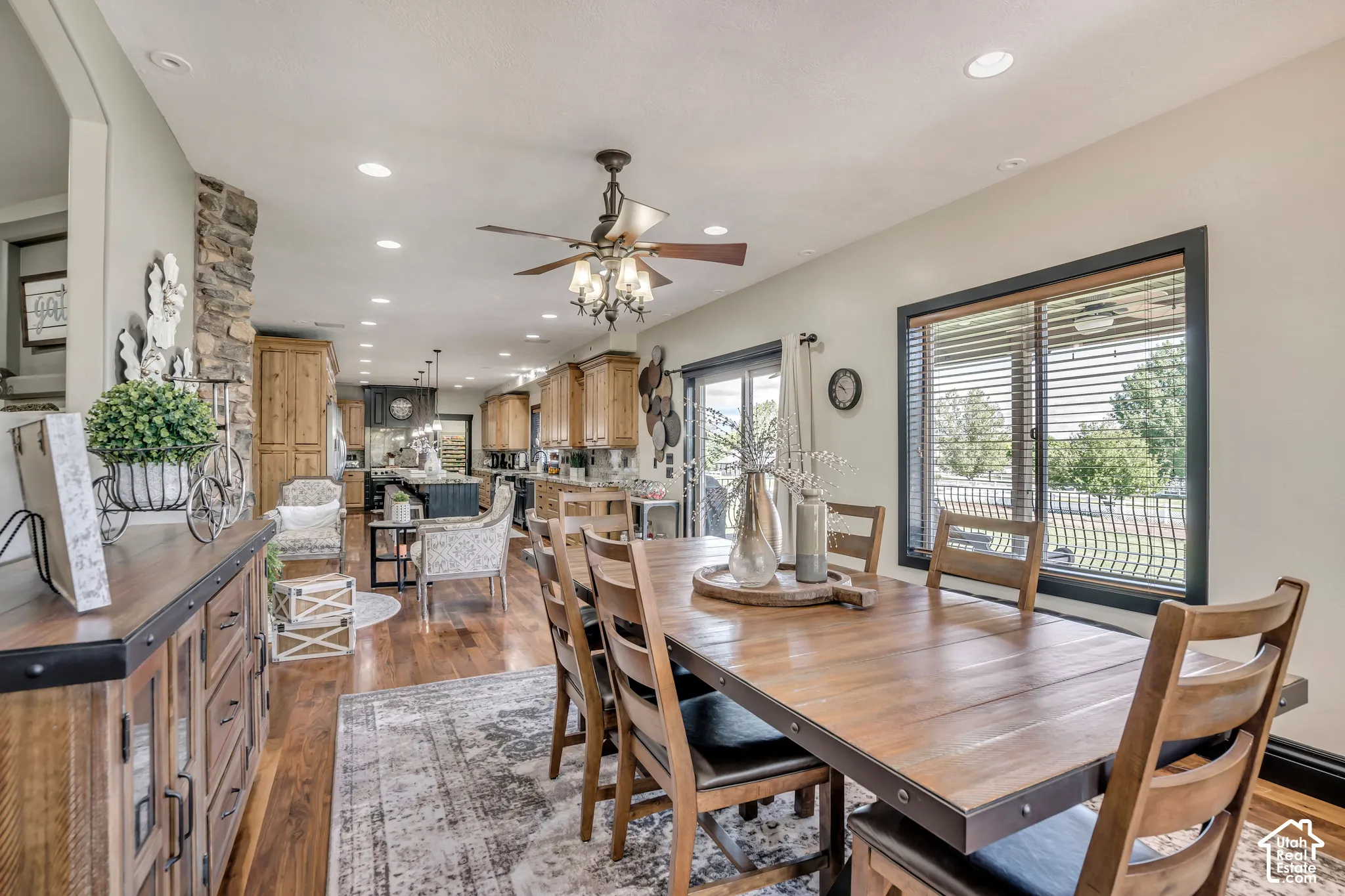 Dining area featuring wood-finish flooring, recessed lighting, a stone-accented wall, and large windows with dark trim