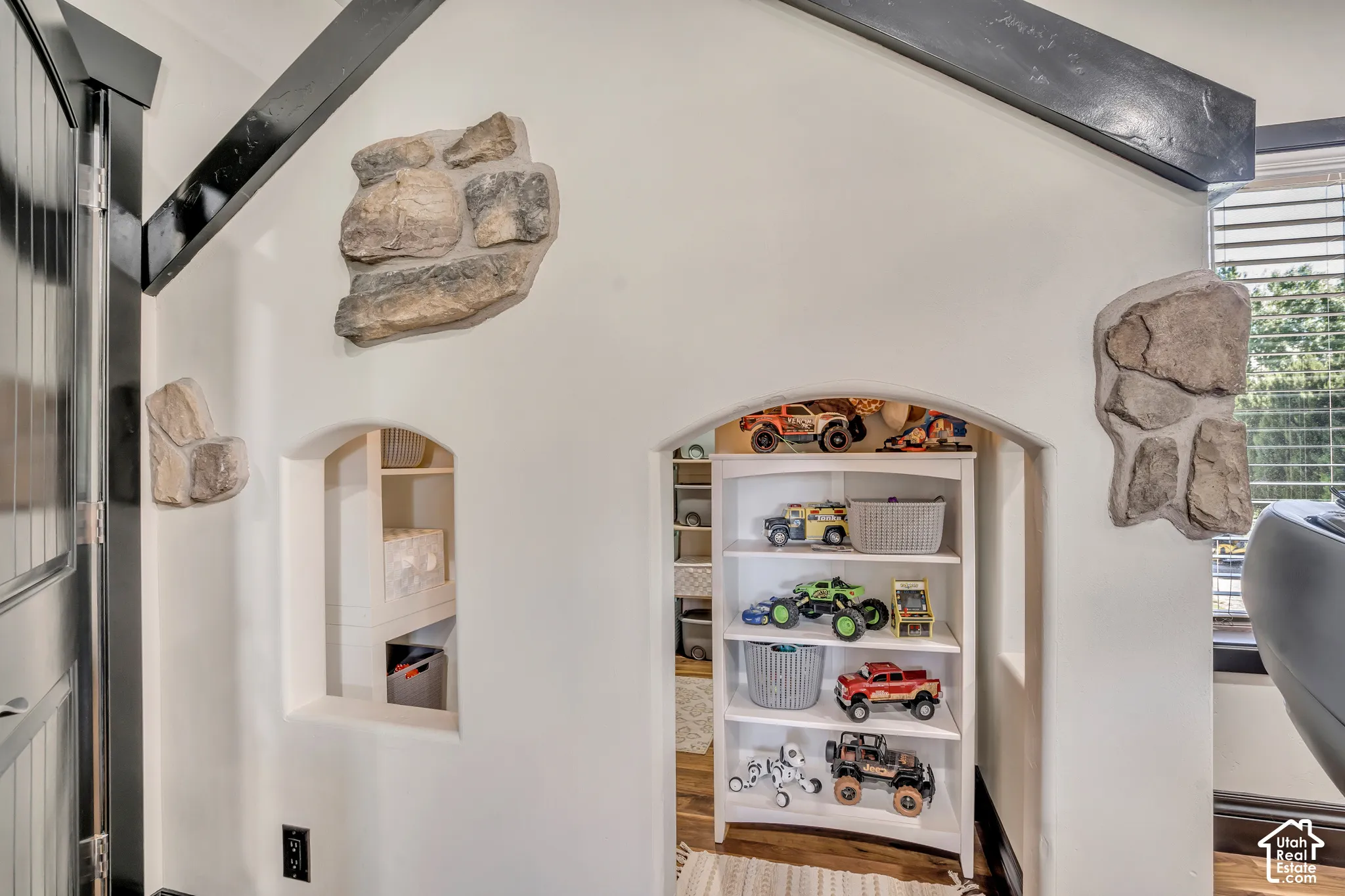 Vaulted ceiling with exposed dark-toned beams, arched wall cutouts, and decorative stone masonry accents