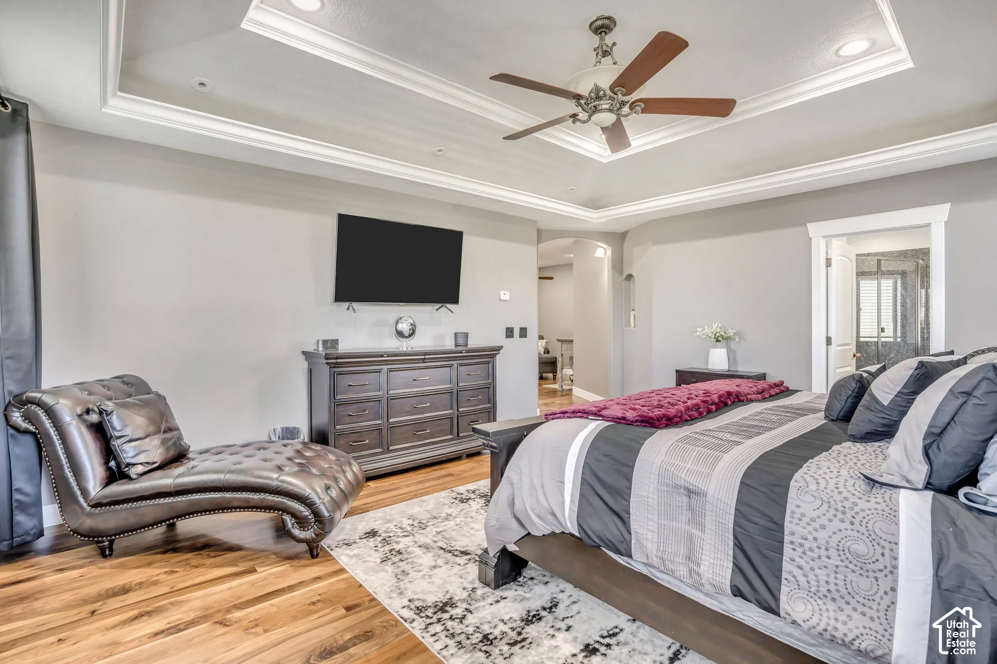 Tray ceiling with recessed lighting, wood-finish flooring, and a ceiling fan