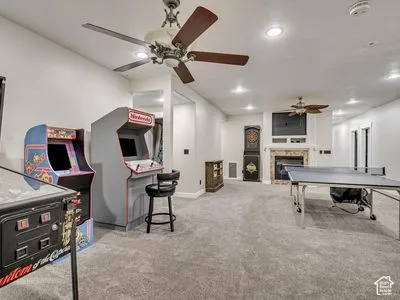 Spacious room featuring neutral carpeting, recessed lighting, dual ceiling fans, and a stone-surround fireplace with a built-in recessed media nook